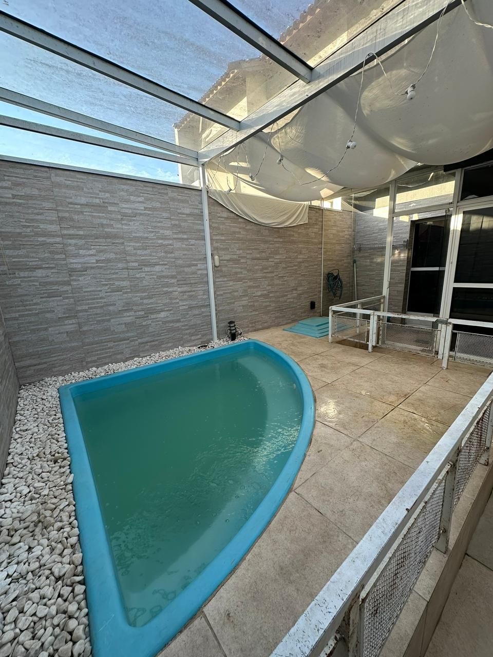 Piscina privativa com cobertura translúcida de policarbonato e pedras decorativas