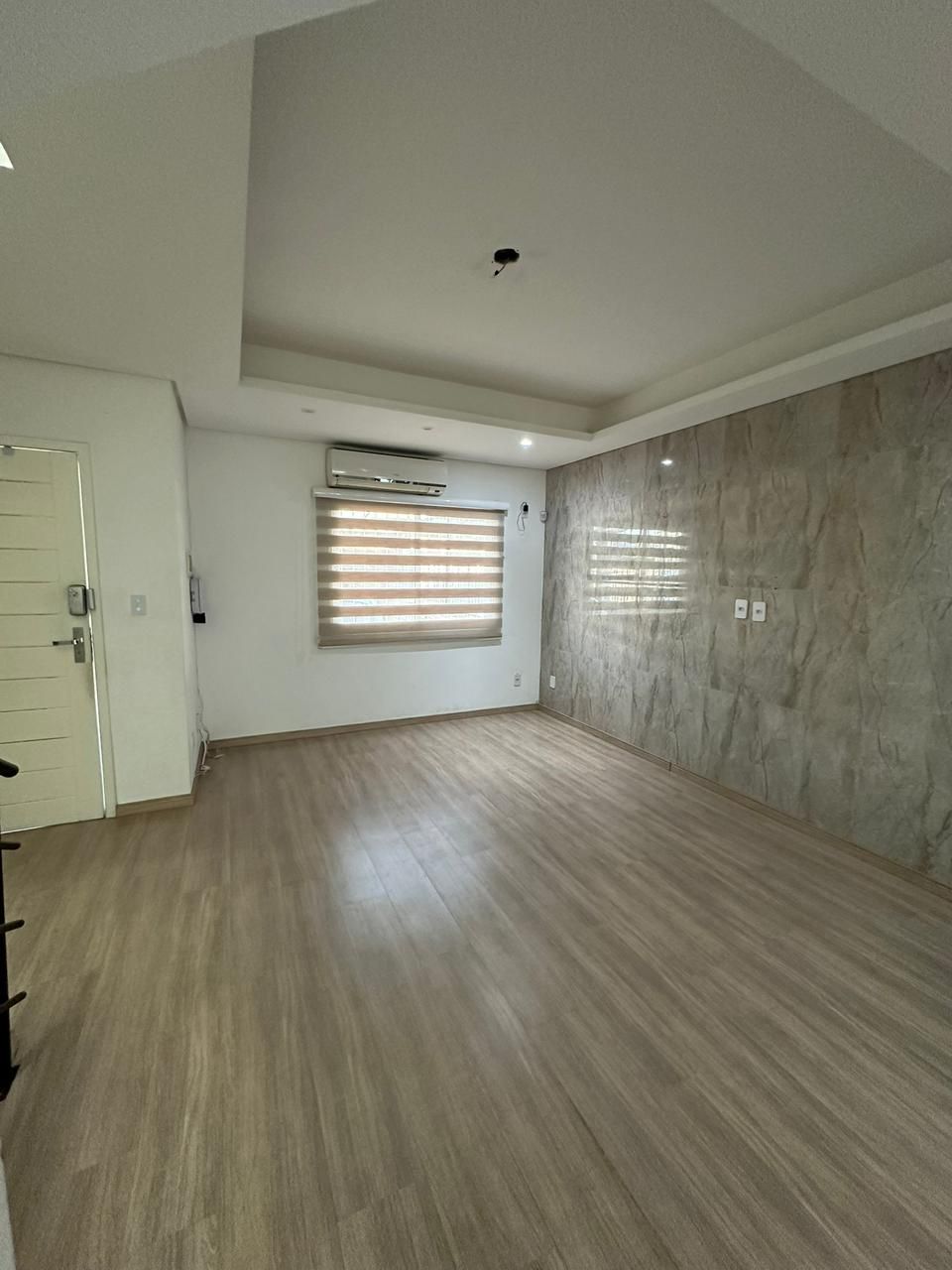 Sala de estar com parede revestida em porcelanato marmorizado para TV