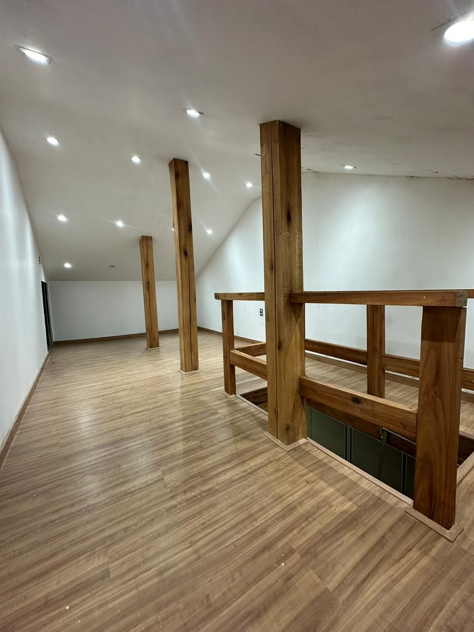 Sótão americano de grande porte com piso laminado e colunas em madeira